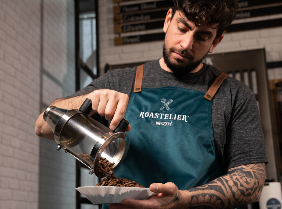 A man carefully pouring hot coffee into a cup, with a warm kitchen background.