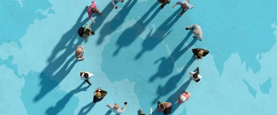 A group of people standing in a circle, their shadows cast on a vibrant blue background.