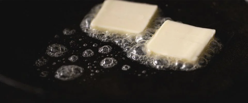 A cooking pan with sautéed green beans and a spoon leaning against the side