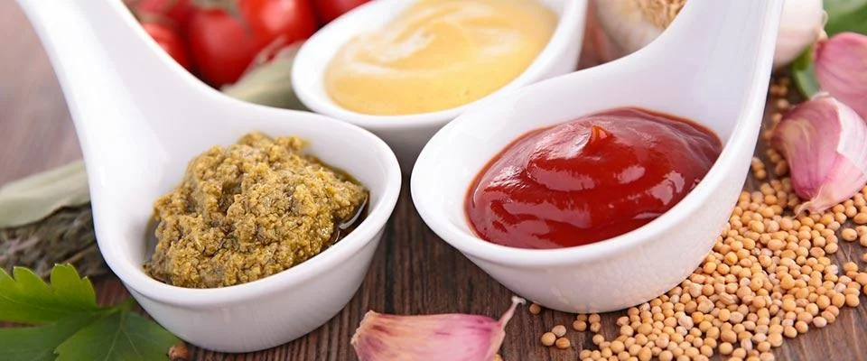 Three small bowls of colorful condiments arranged neatly on a table.