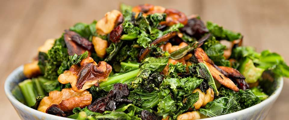 A bowl with fresh greens and a mix of crunchy nuts on top, creating a healthy and colorful dish.