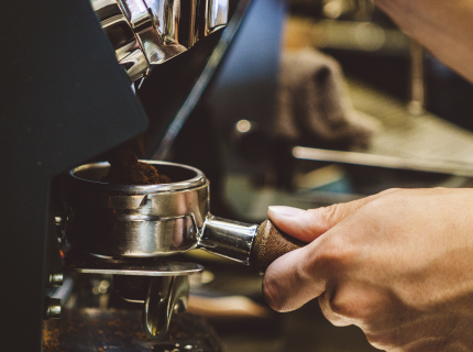 A person operates an espresso machine, skillfully preparing a fresh cup of coffee.