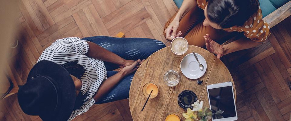 Two people chatting at a table in a restaurant setting