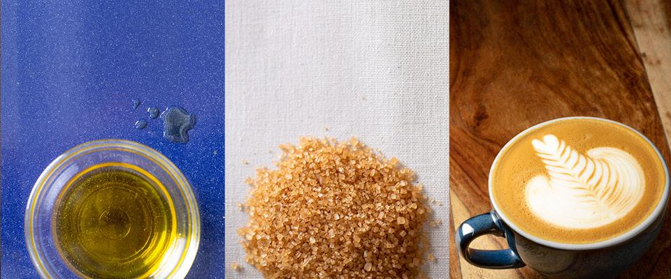 A coffee cup filled with a plant-based beverage, accompanied by a spoon and a small bowl of sugar.