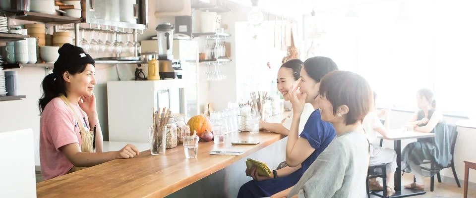 A group of women enjoying conversation at a cafe, potentially discussing plant-based products.