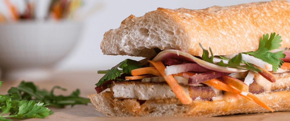 A sandwich filled with tofu and fresh veggies, showcasing hidden plant-based diet options.