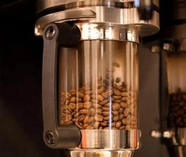Coffee beans are being ground in a machine, releasing rich aromas and preparing for a fresh brew.