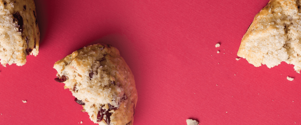 A red background featuring a whole cookie beside a half-eaten cookie, highlighting their textures and colors.