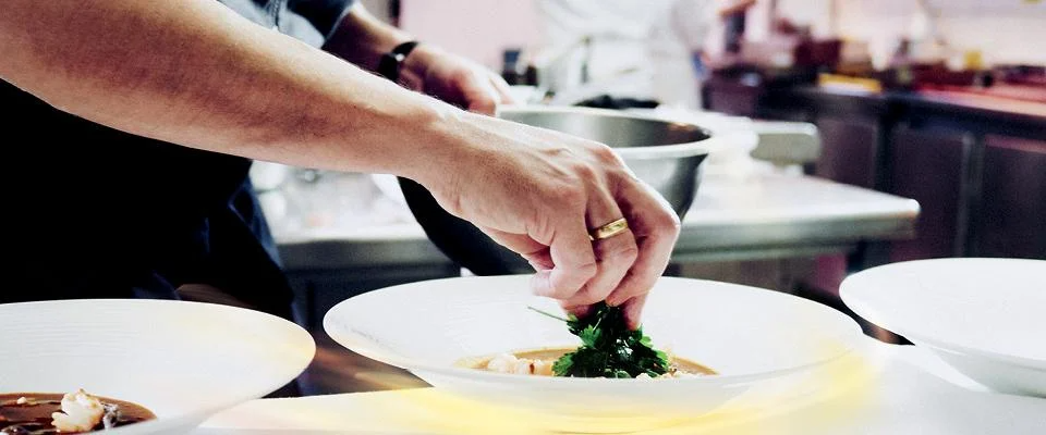 A chef skillfully prepares ingredients in a busy kitchen, surrounded by pots and pans.