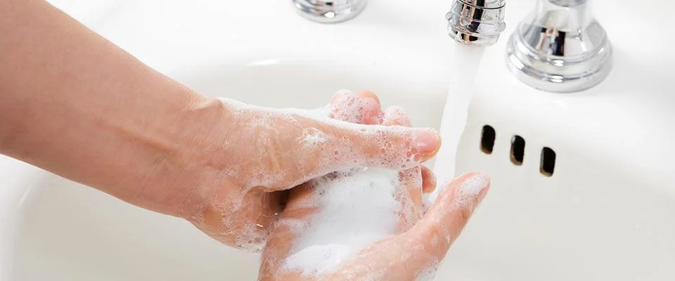 A person is washing their hands thoroughly in a sink, ensuring cleanliness and hygiene.