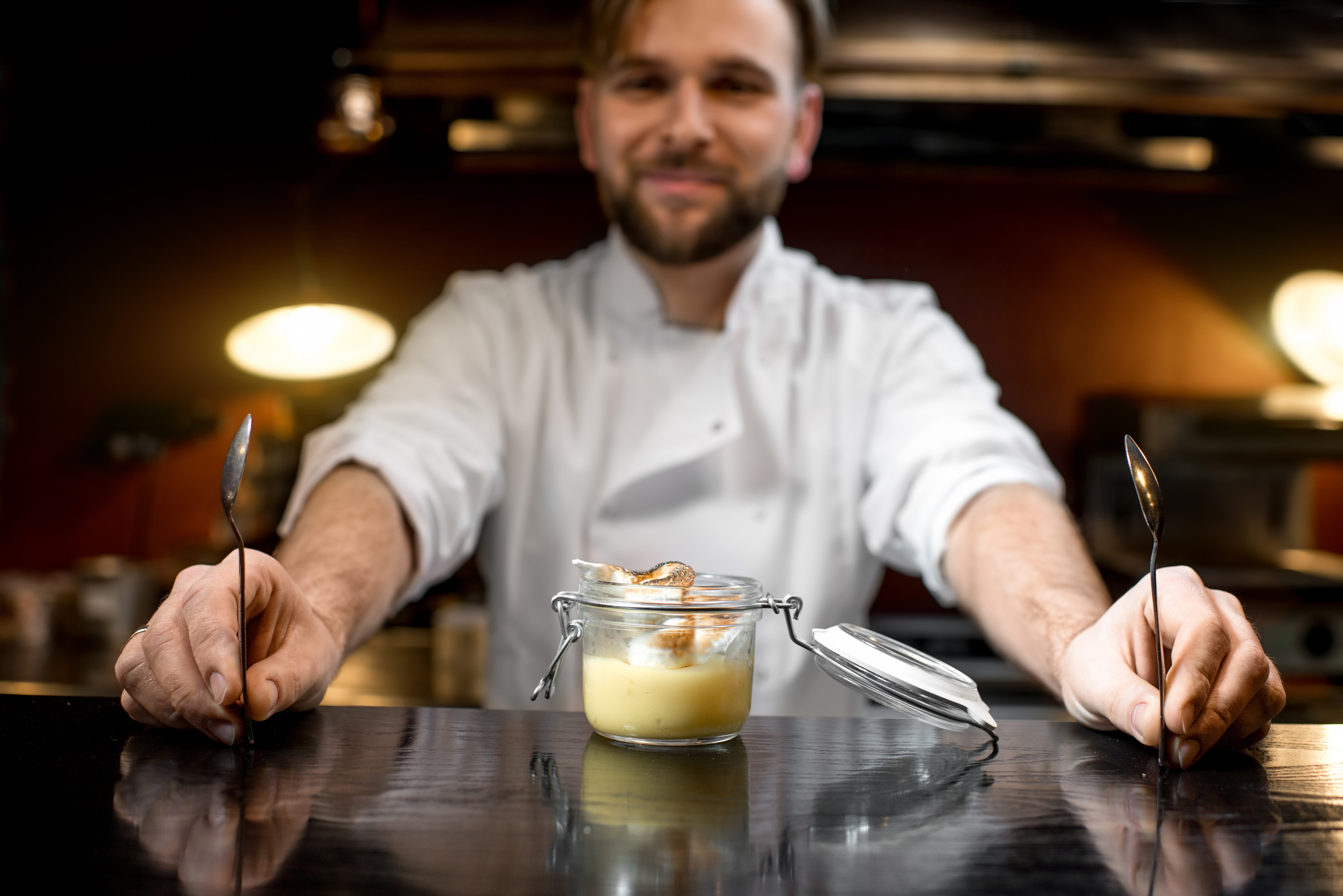 A chef presents a dessert in a jar, showcasing skills to improve head chef job prospects.