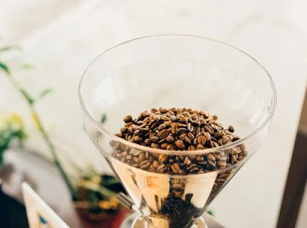 A coffee grinder placed on a wooden table, ready for grinding fresh coffee beans.