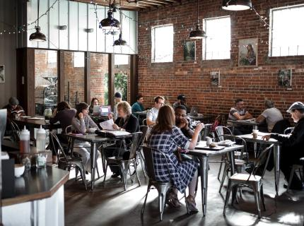 A cozy restaurant scene with people dining at tables surrounded by warm brick walls.