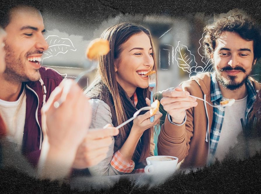 A group of friends joyfully sharing a meal together, smiling and enjoying each other's company.