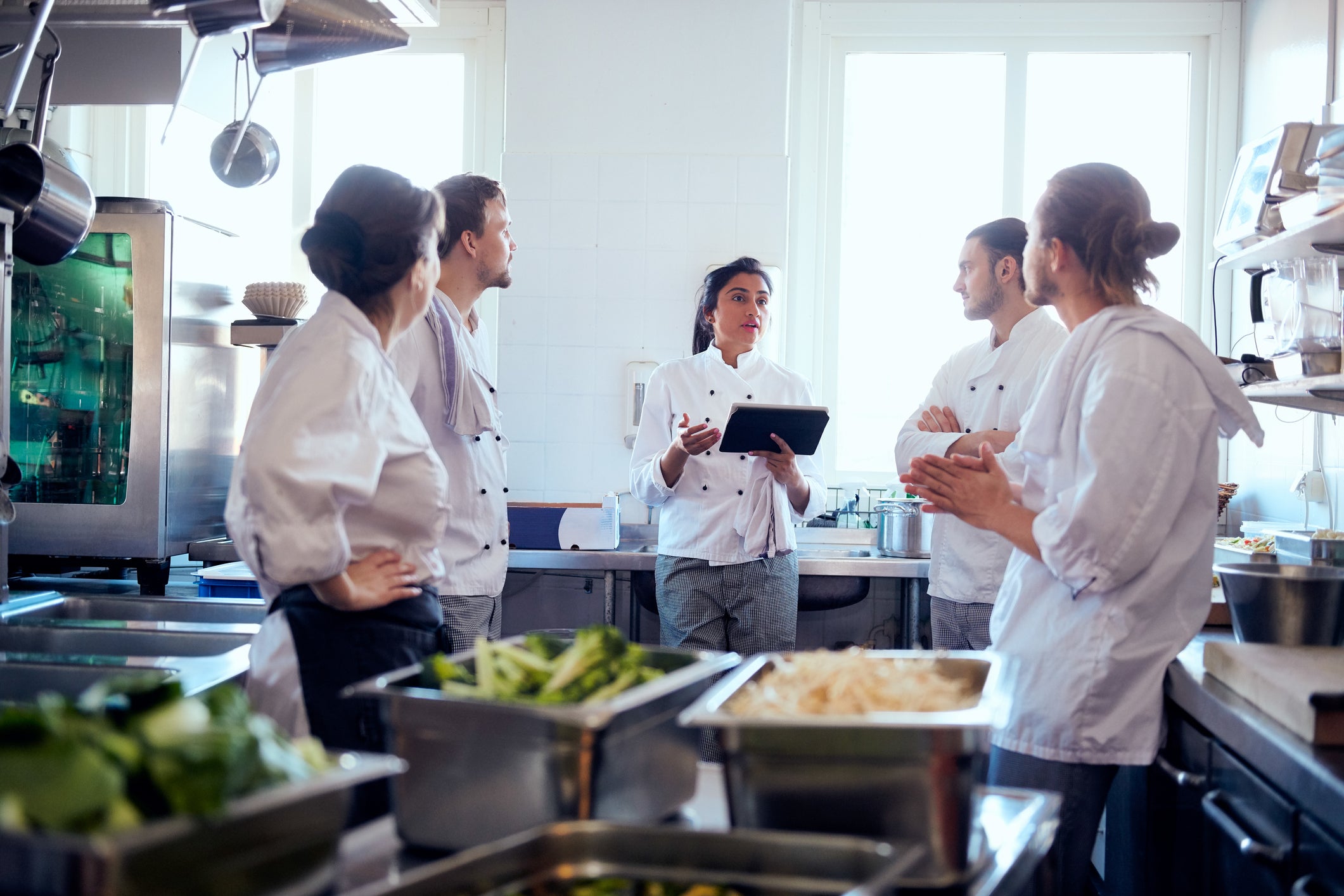 Chefs in white uniforms standing together in a bustling kitchen, ready to prepare delicious meals.