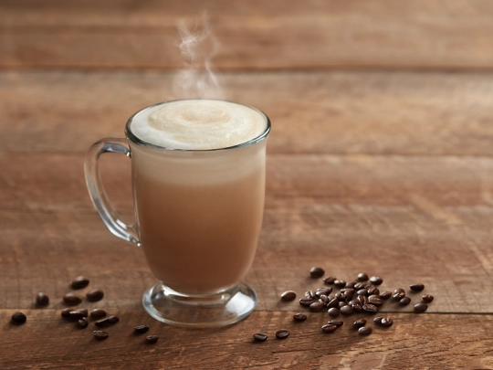 A steaming glass of coffee sits on a table, inviting warmth and comfort with its rich aroma.