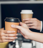 Individuals seated in a restaurant, each holding coffee cups.