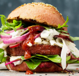 A delicious burger topped with fresh lettuce, onions, and ripe tomatoes, ready to be enjoyed.