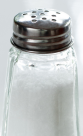 A salt shaker filled with white salt, resting on a wooden table.