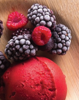 A bowl filled with creamy ice cream topped with fresh berries and vibrant raspberries.