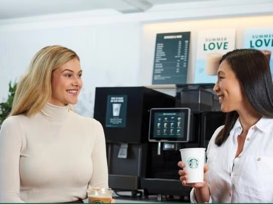 Starbucks ad featuring a woman and a man, both smiling, promoting a sense of community and connection.