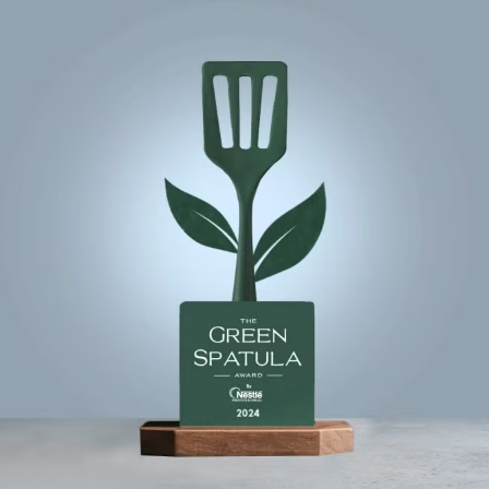 A green spatula award resting on a table, representing achievement in cooking or culinary arts.