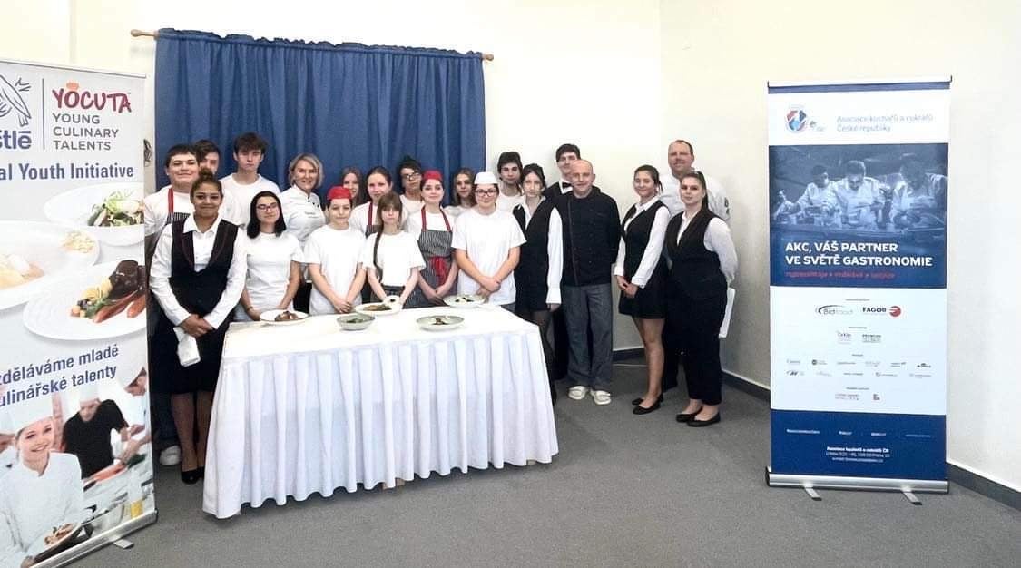 Several individuals standing together for a photo, with a table visible in the foreground, showcasing a social gathering.