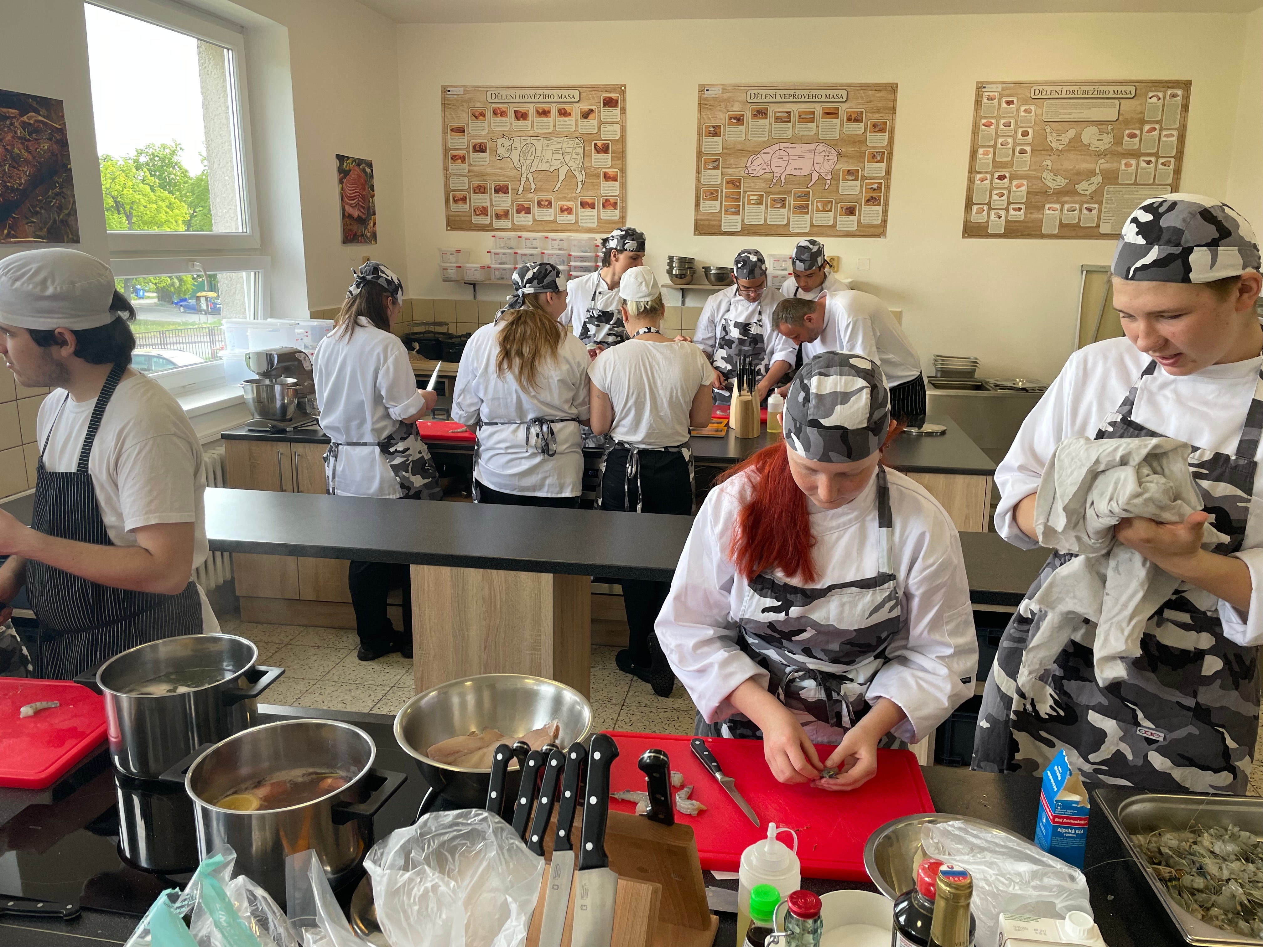 A diverse group of people in a kitchen, working together to prepare food, surrounded by ingredients and cooking tools.