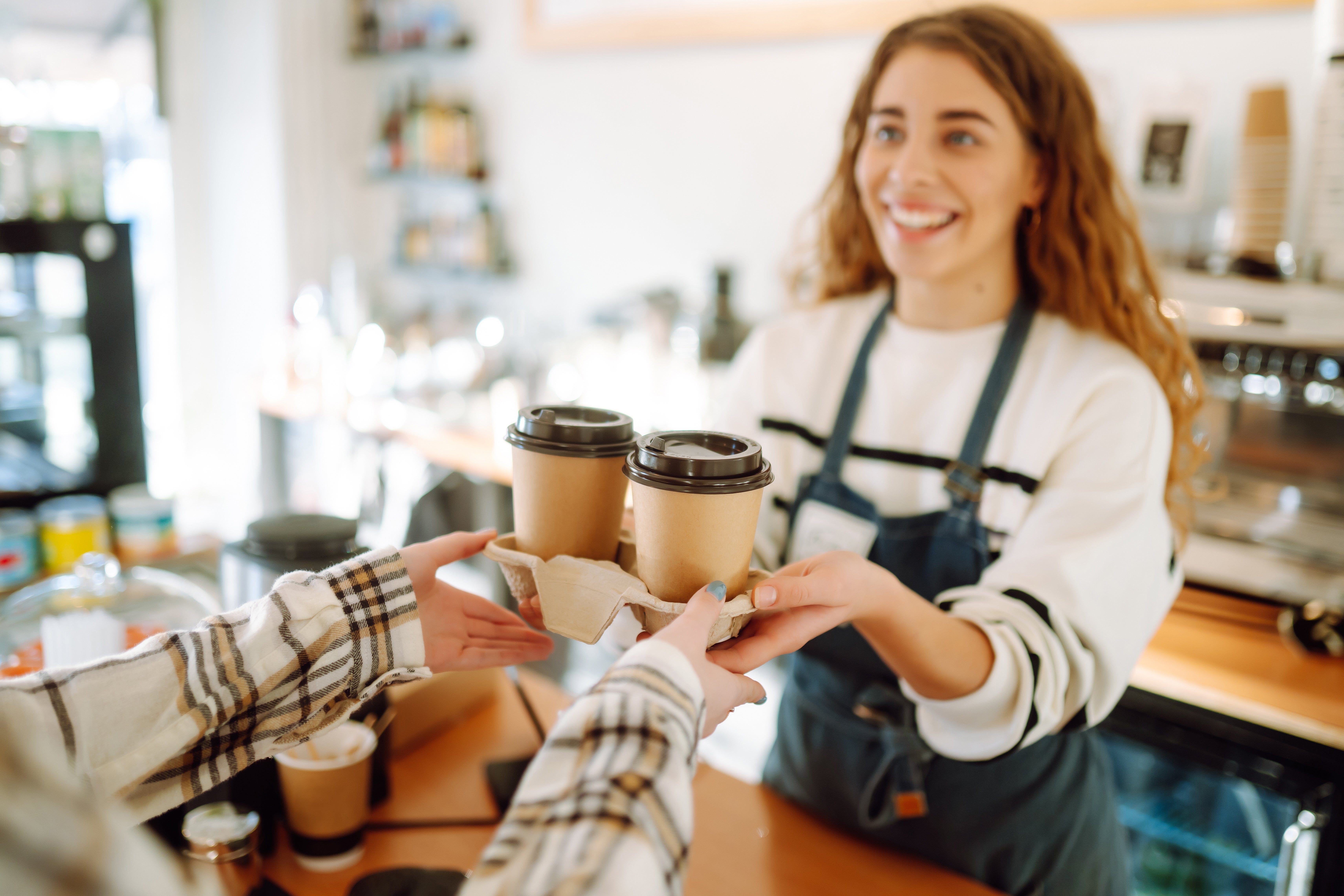 A woman is holding a coffee cup, facing another woman, suggesting a moment of connection and conversation.