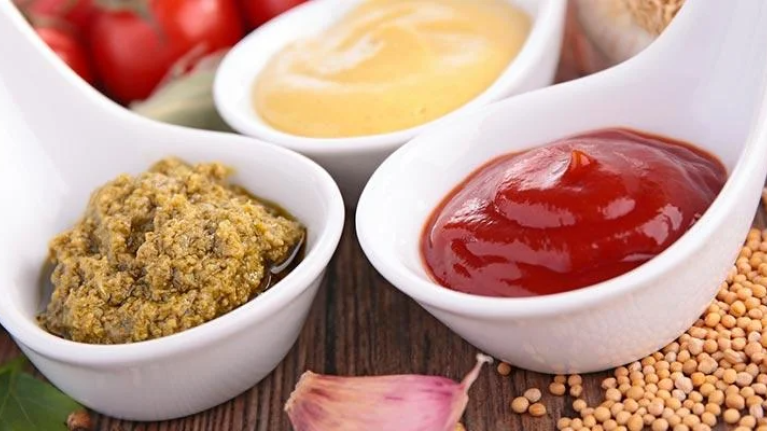 Three small bowls of colorful condiments arranged neatly on a table.