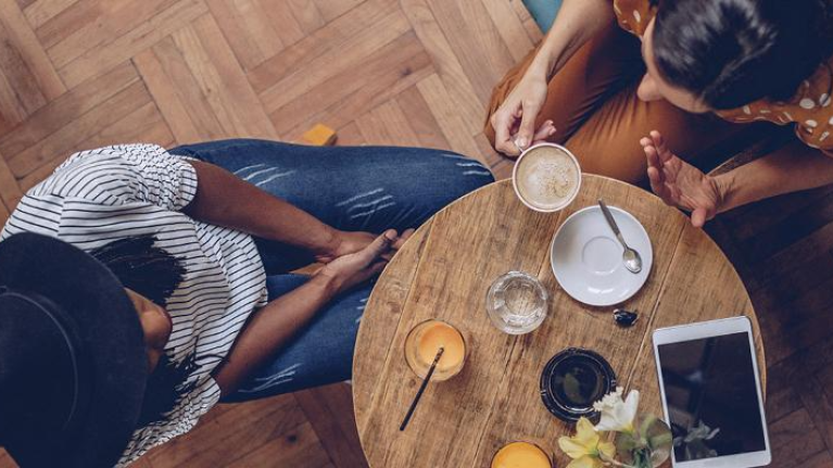 Two people chatting at a table in a restaurant setting