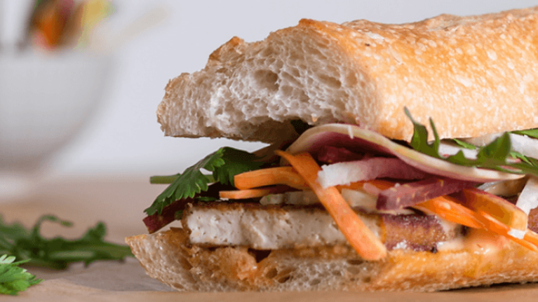 A sandwich filled with tofu and fresh veggies, showcasing hidden plant-based diet options.
