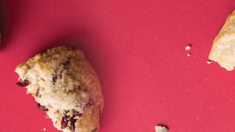 A red background featuring a whole cookie beside a half-eaten cookie, highlighting their textures and colors.
