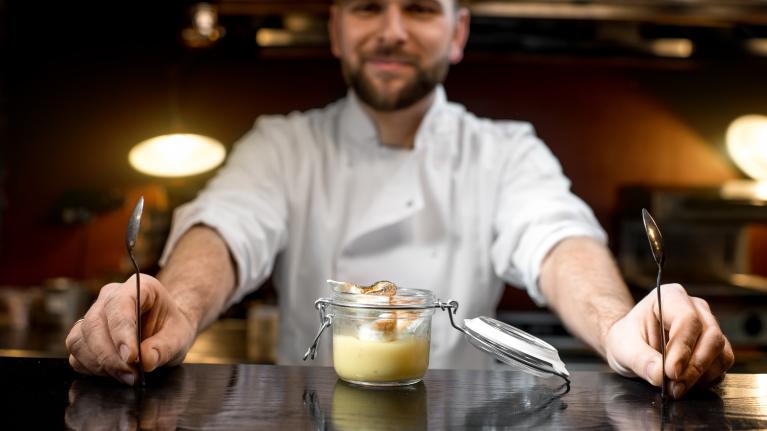 A chef presents a dessert in a jar, showcasing skills to improve head chef job prospects.