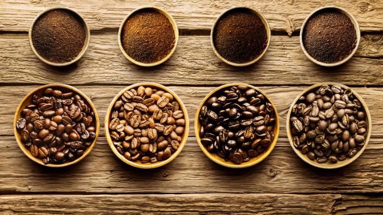 A table with bowls filled with various coffee beans, showcasing their rich colors and textures.