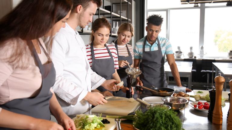A diverse group of individuals collaborates in a kitchen, skillfully preparing various dishes together.