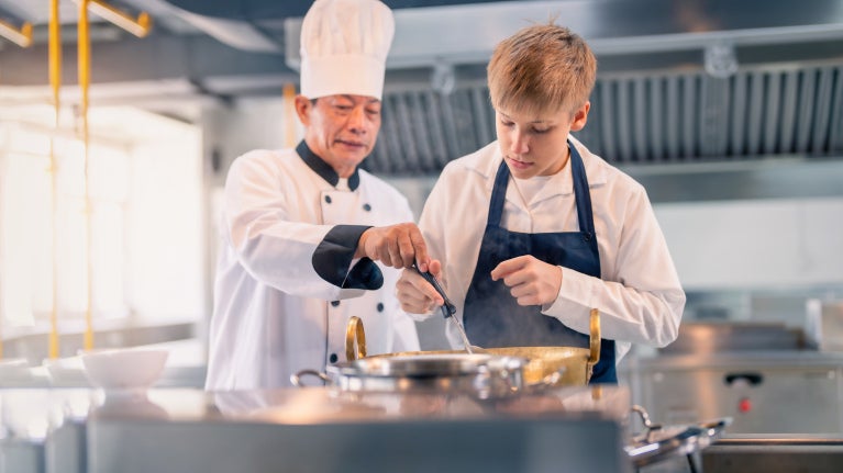 Asian chef teaching cooking to a young chef