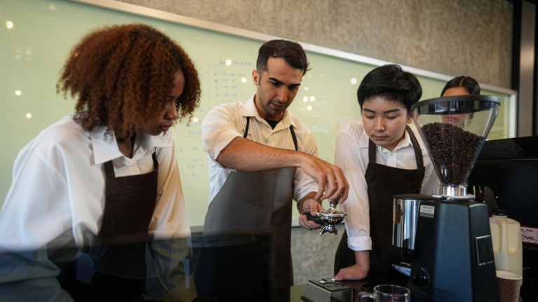 Master barista teaching and showing how to prepare coffee to gen z students