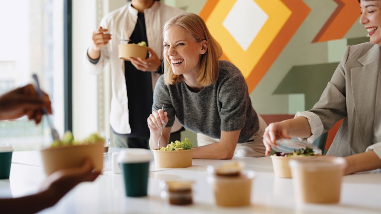 Woman in an office environment having lunch with colleagues
