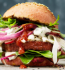 A delicious burger topped with fresh lettuce, onions, and ripe tomatoes, ready to be enjoyed.