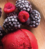A bowl filled with creamy ice cream topped with fresh berries and vibrant raspberries.