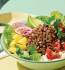 A colorful bowl of meat, lettuce, and assorted ingredients featured in the Garden Gourmet Plant Proteins Bowl Recipe Booklet.
