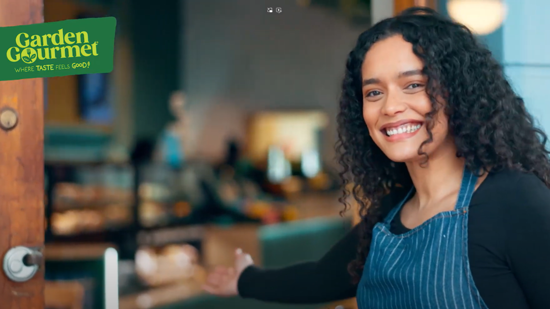 A smiling woman stands in front of a closed door, radiating happiness and warmth.