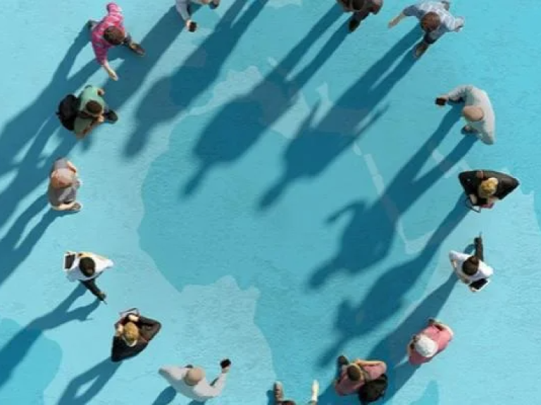 A group of people standing in a circle, their shadows cast on a vibrant blue background.