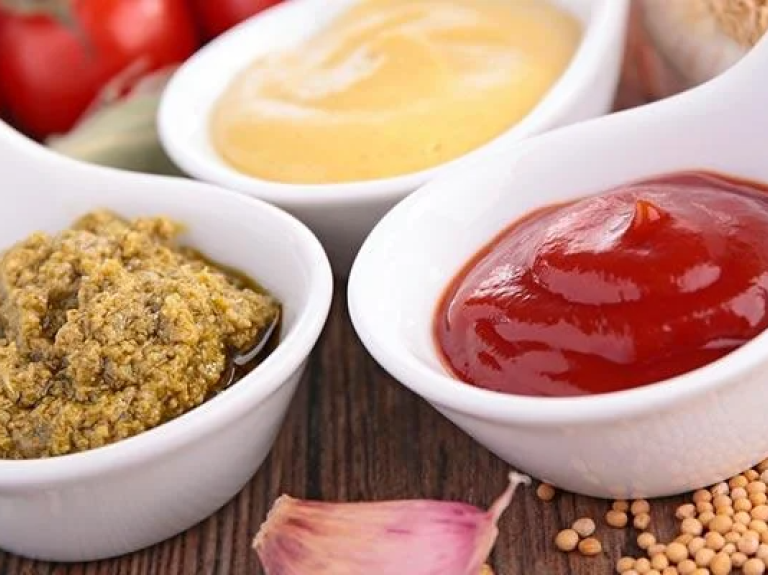 Three small bowls of colorful condiments arranged neatly on a table.
