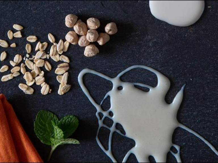 A bowl filled with assorted nuts, milk, and spices elegantly arranged on a wooden table.
