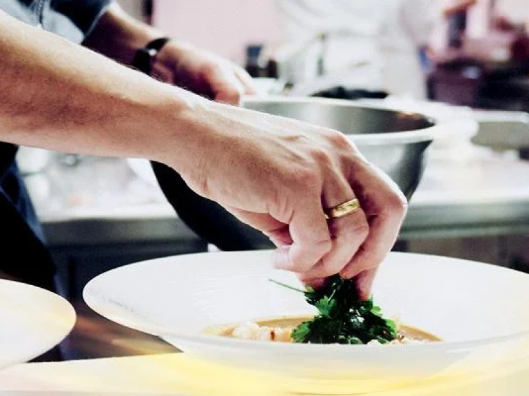A chef skillfully prepares ingredients in a busy kitchen, surrounded by pots and pans.