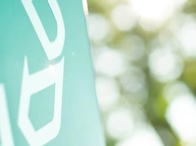 Close-up of a green sign displaying some bold letters.
