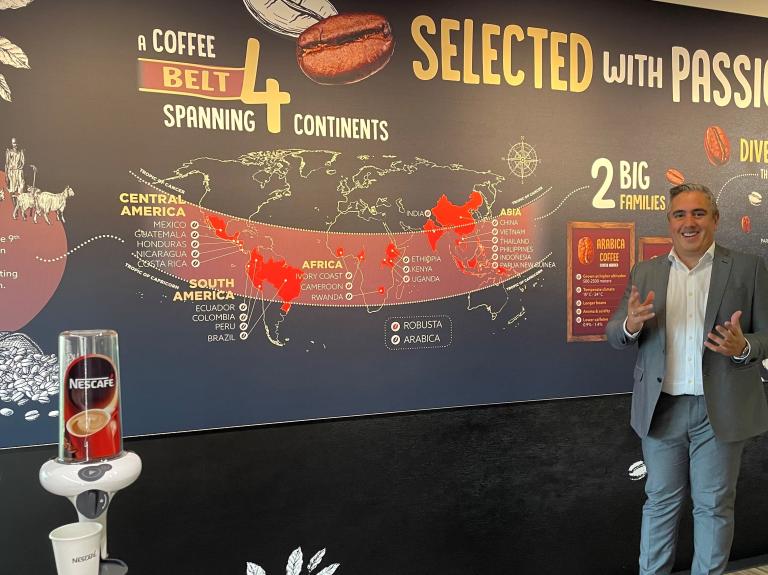 A man stands in front of a wall, next to a coffee machine, ready to brew a fresh cup of coffee.