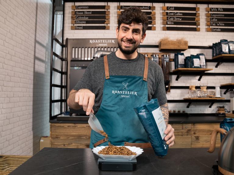 A man smiles while holding a bowl of food, ready to serve a delicious meal.
